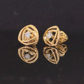 Pair of gold earrings with diamond accents on black background
