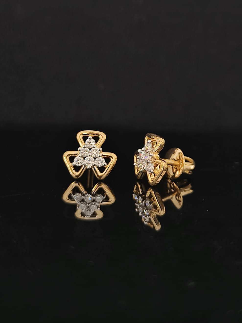 Pair of gold earrings with 0.23 carat diamonds on black background
