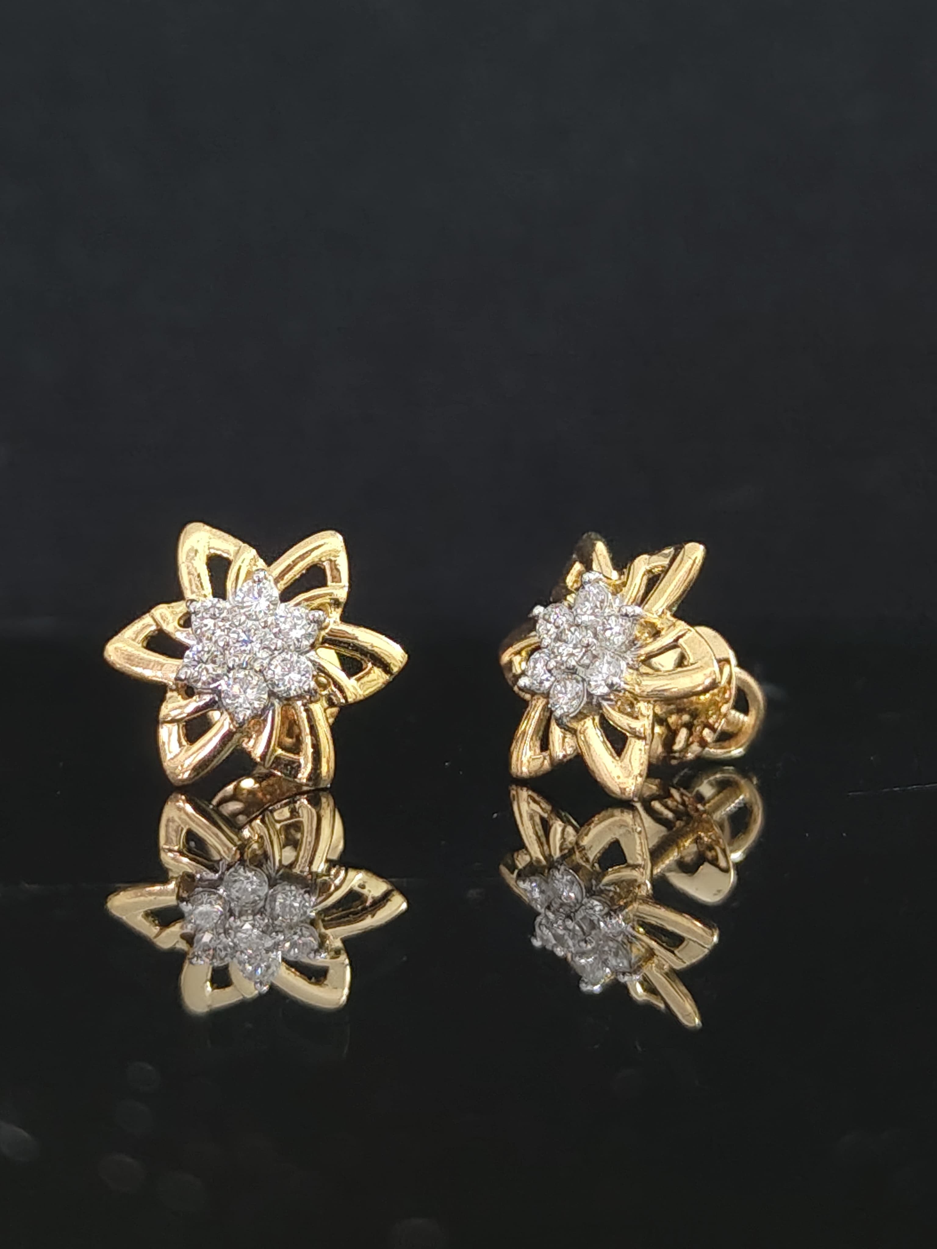 Pair of gold earrings with 0.3 carat diamonds on black background
