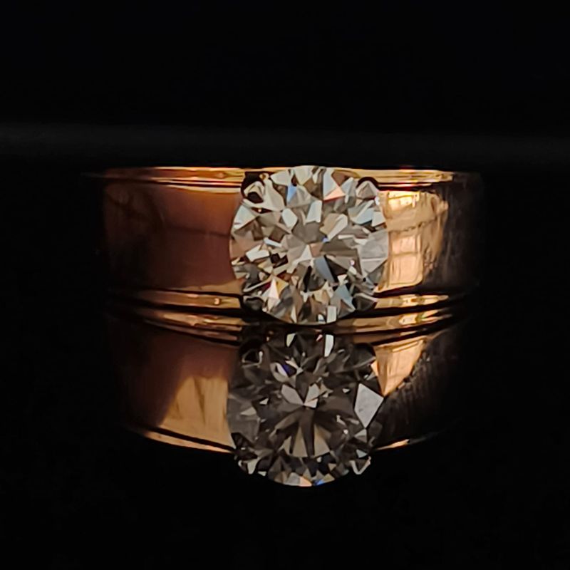Gold ring with large diamond stone on reflective surface
