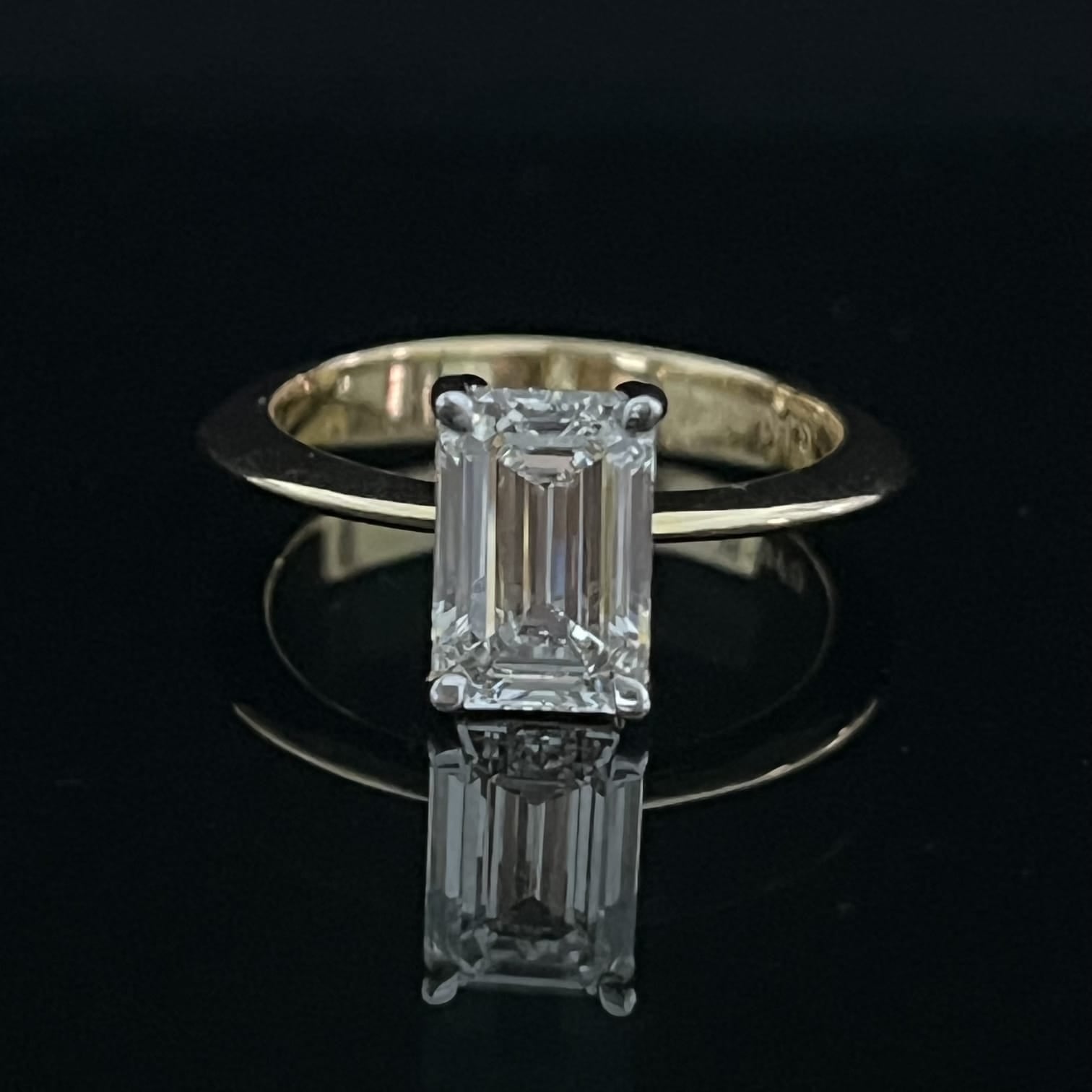 Diamond ring with emerald-cut gemstone on a black background