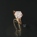 Rose gold ring with a diamond on a black background